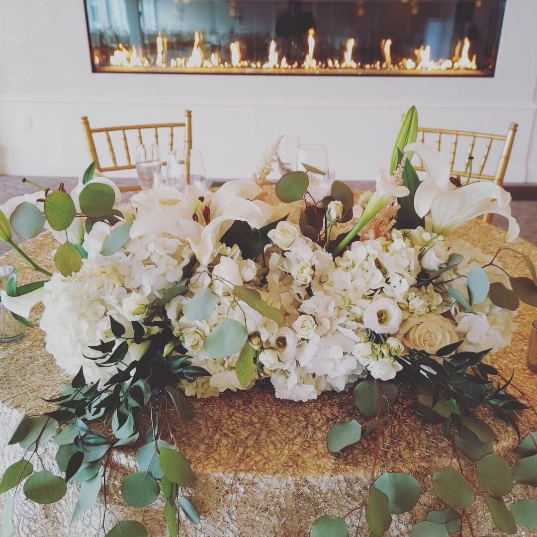 White and gold wedding sweetheart table with lilies and roses